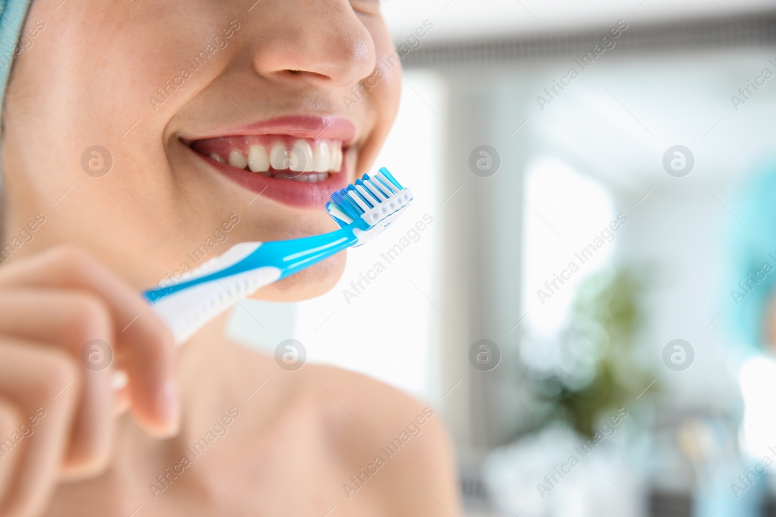 Photo of Young woman with toothbrush on blurred background, closeup. Space for text