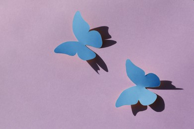 Bright light blue paper butterflies on violet background