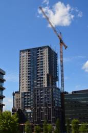 Tower crane near unfinished buildings against blue sky