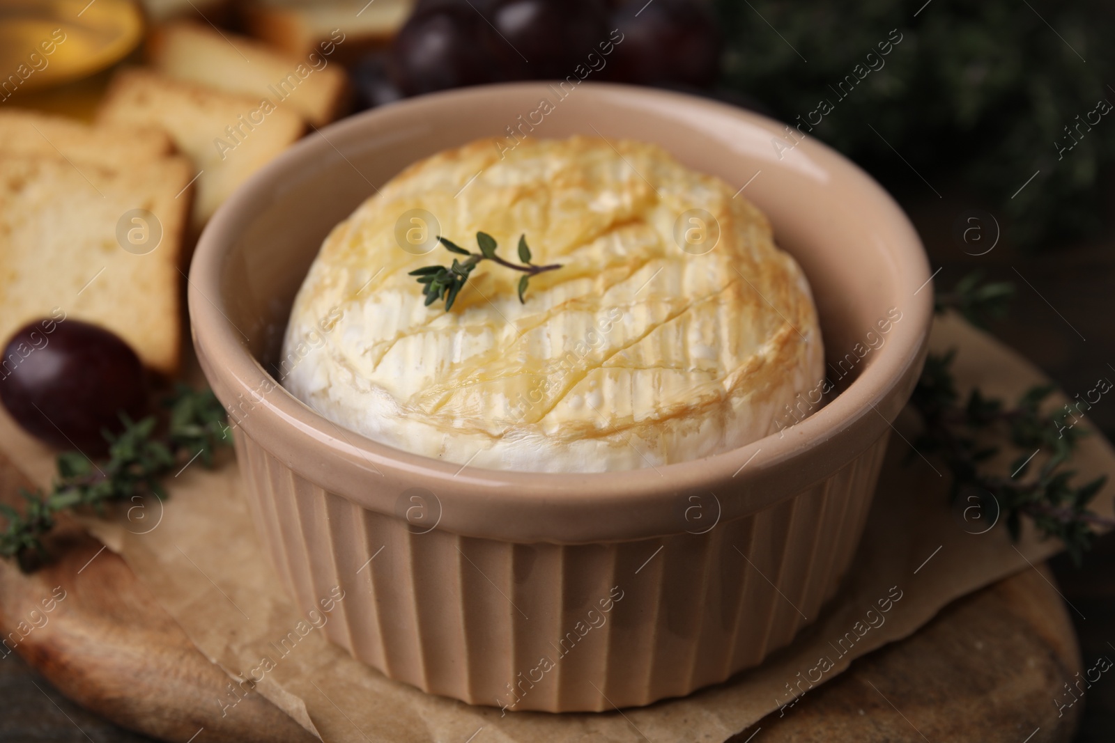 Photo of Tasty baked camembert in bowl on table, closeup