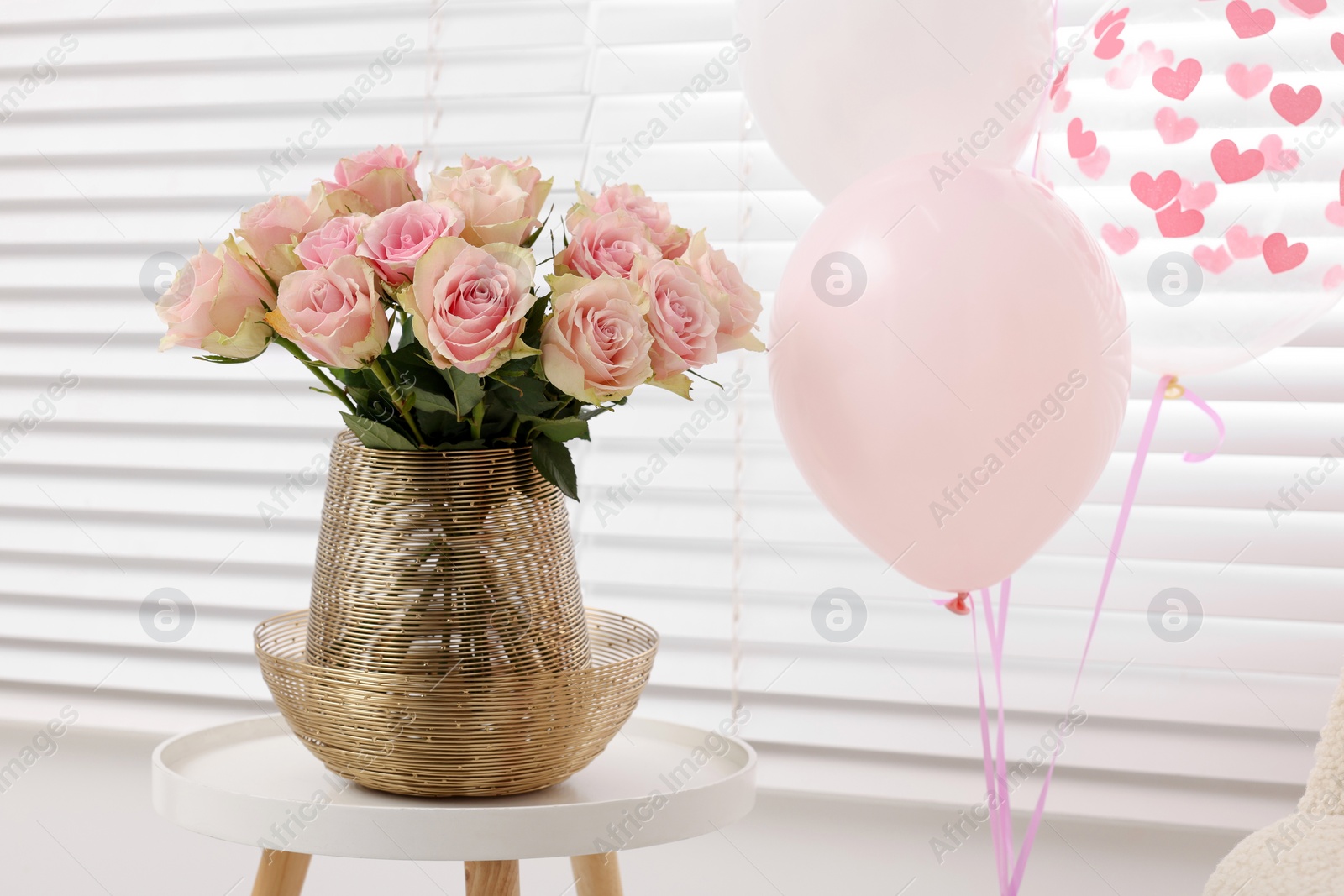Photo of Beautiful bouquet of rose flowers in vase and air balloons in room. Happy birthday