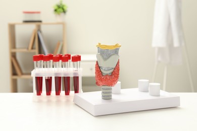 Endocrinology. Model of thyroid gland and samples of blood in test tubes on white table at clinic