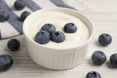 Bowl of yogurt with blueberries served on white wooden table