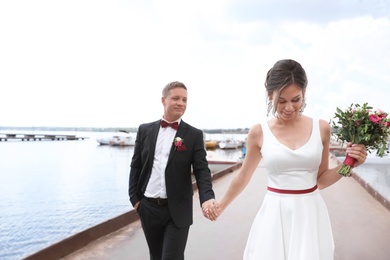 Photo of Happy newlyweds with beautiful bridal bouquet near river