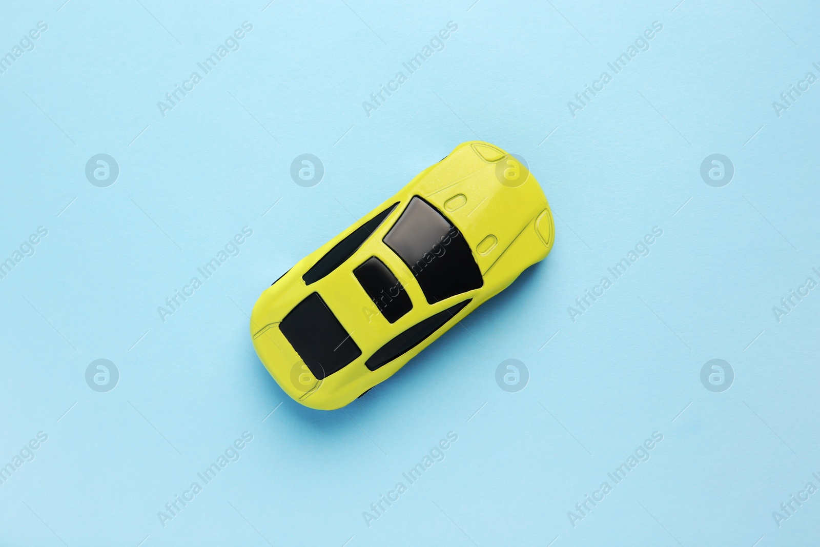 Photo of One yellow car on light blue background, top view. Children`s toy