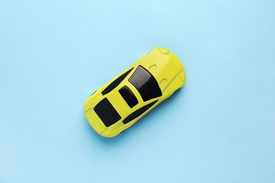 One yellow car on light blue background, top view. Children`s toy