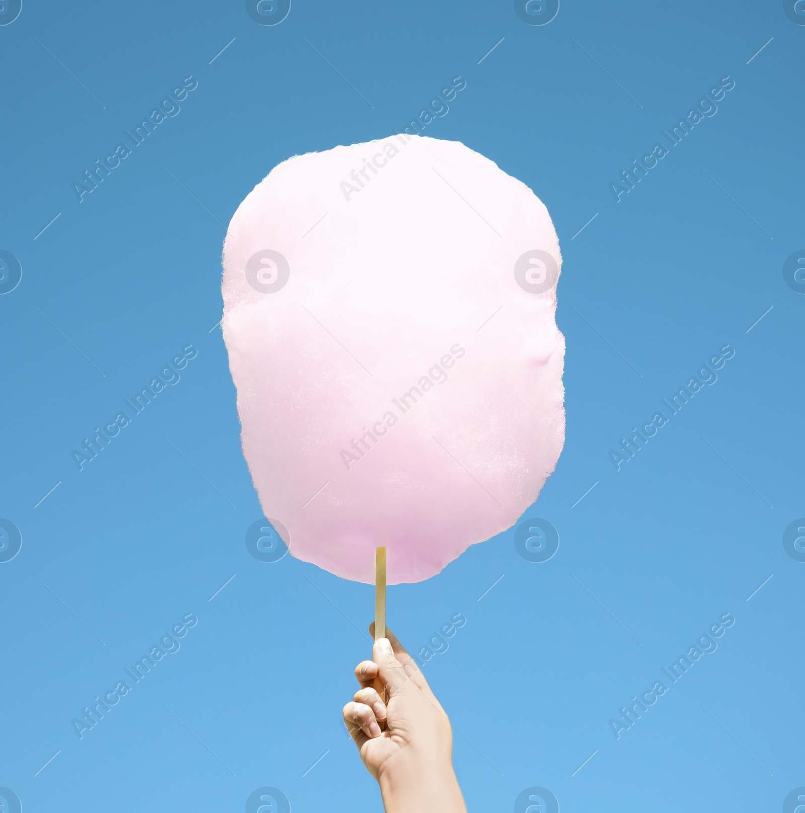 Photo of Woman holding white cotton candy against blue sky