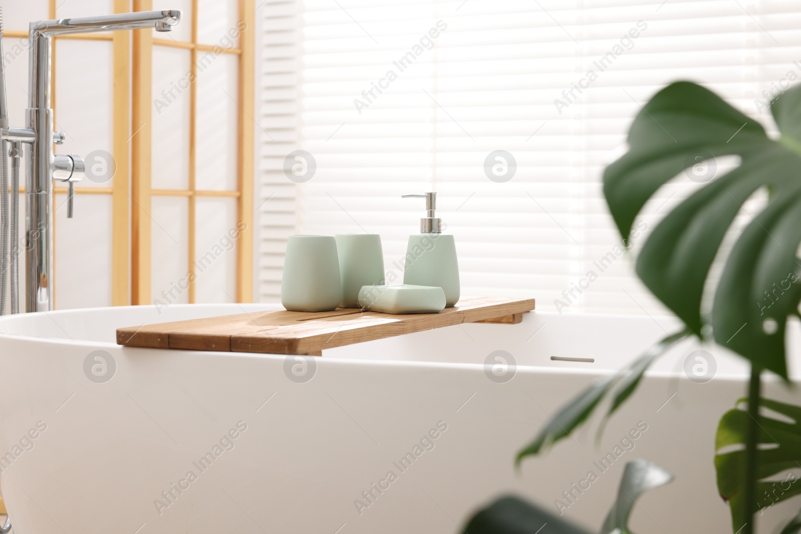 Photo of Set of bath accessories on tub in bathroom