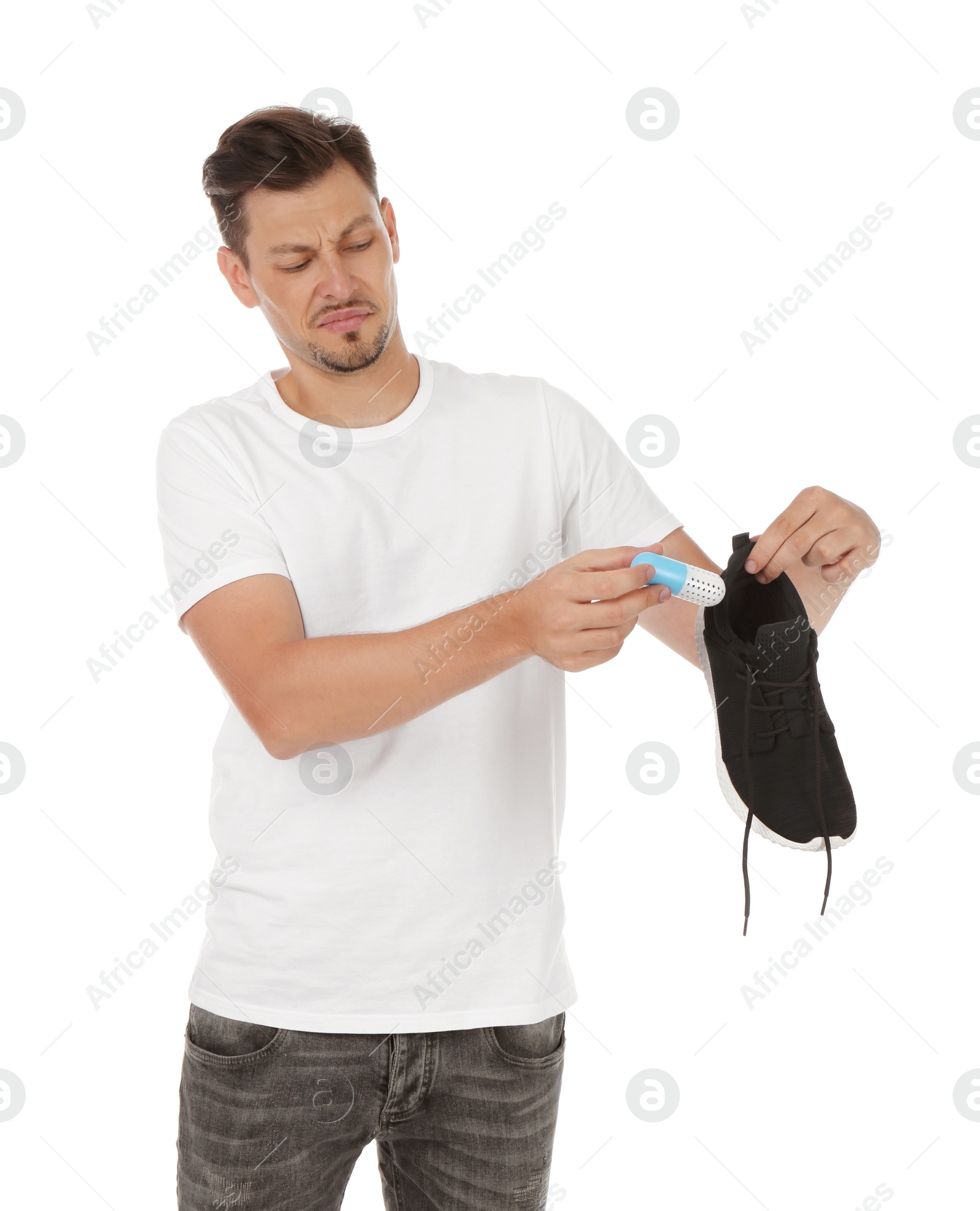 Photo of Man putting capsule shoe freshener in footwear on white background