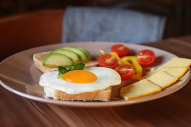 Photo of Tasty toasts with fried egg, avocado, cheese and vegetables on wooden table, closeup