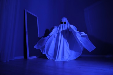 Creepy ghost. Woman covered with sheet in blue light