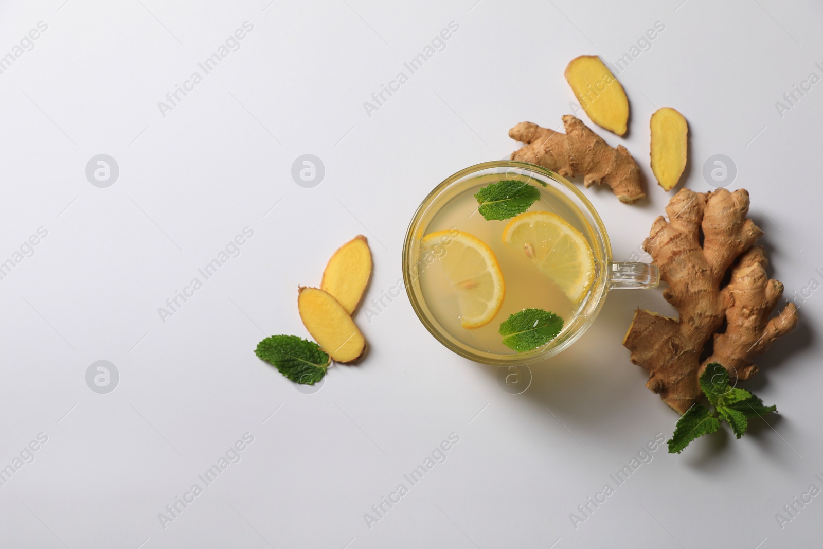 Photo of Delicious ginger tea, lemon and mint on light grey background, flat lay. Space for text