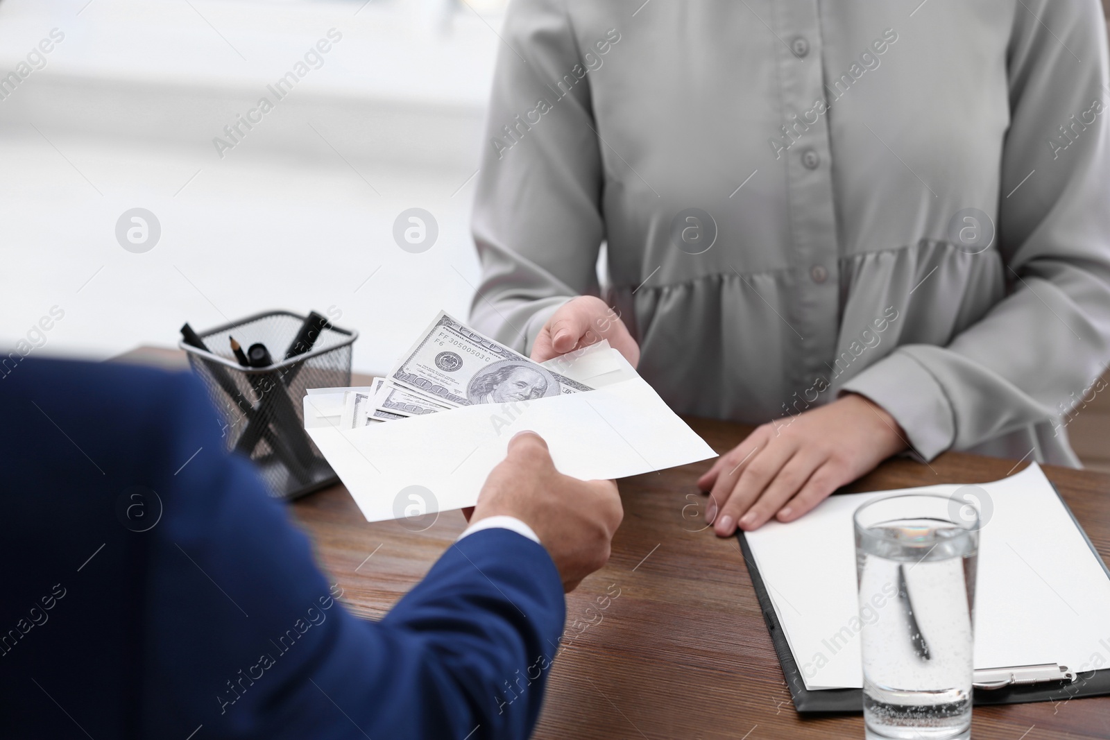 Photo of Man giving bribe money to woman at table, closeup