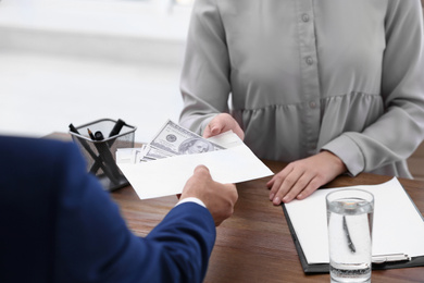 Photo of Man giving bribe money to woman at table, closeup