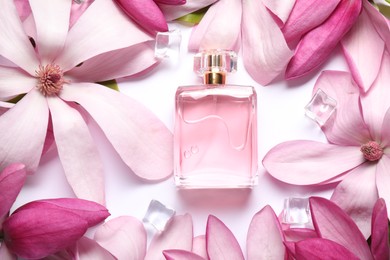 Beautiful pink magnolia flowers, bottle of perfume and ice cubes on white background, flat lay