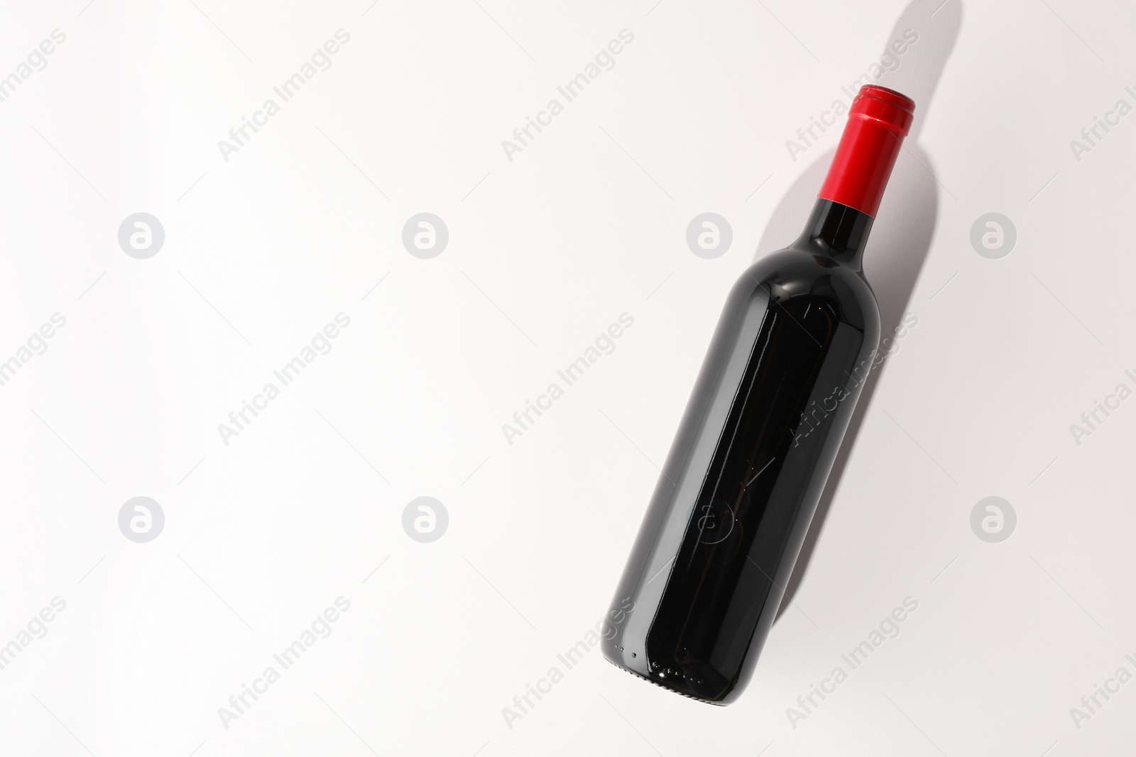 Photo of Bottle of expensive red wine on white background, top view. Space for text
