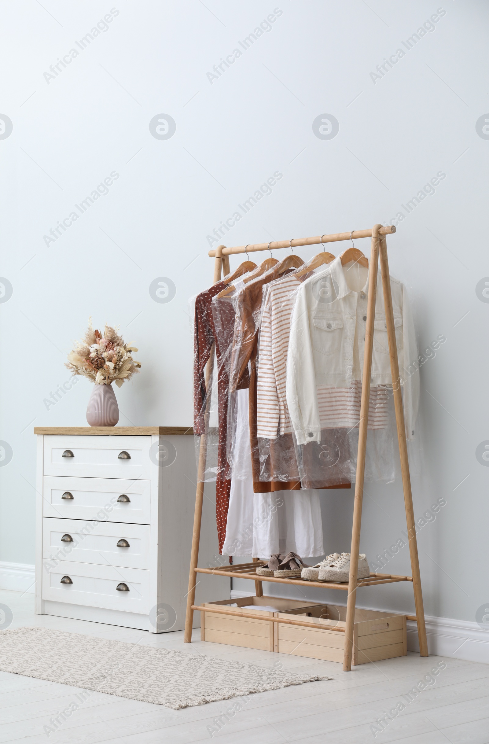 Photo of Rack with clothes in plastic bags indoors