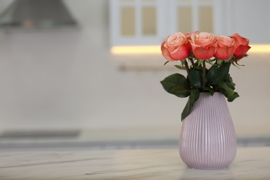 Photo of Vase with beautiful roses on white marble kitchen table, space for text. Interior design