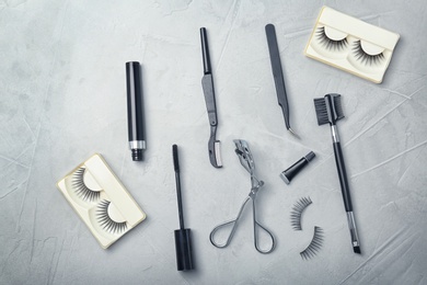 Photo of Flat lay composition with false eyelashes and cosmetic tools on grey background