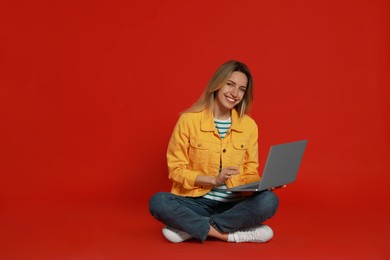 Young woman with modern laptop on red background