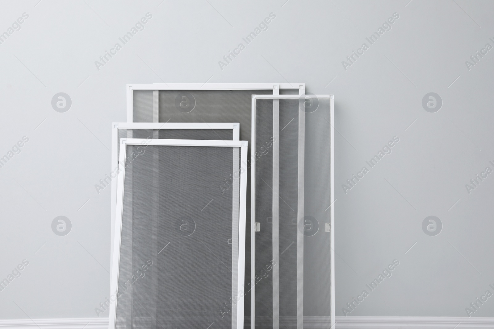 Photo of Set of window screens near light grey wall indoors. Space for text