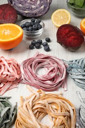 Photo of Rolled pasta painted with natural food colorings and ingredients on white wooden table