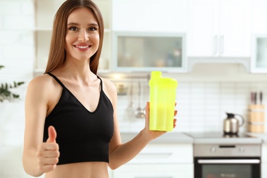 Photo of Young woman with bottle of protein shake in kitchen