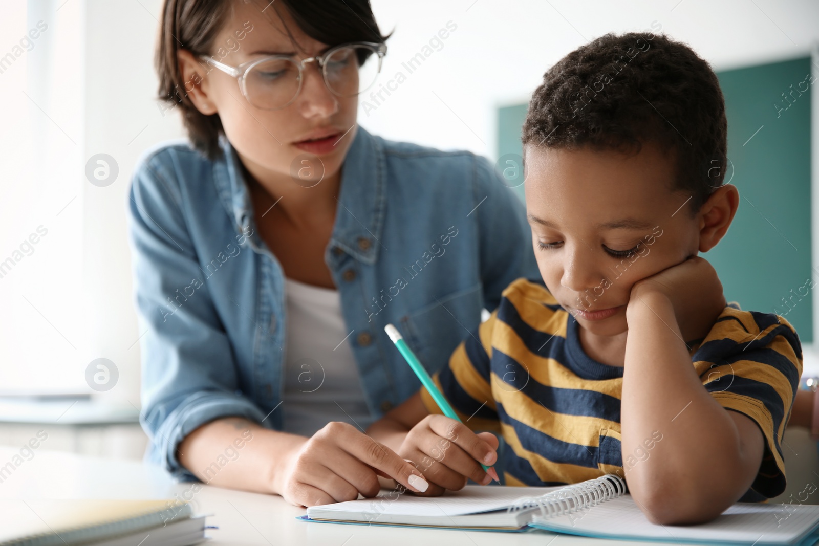 Photo of Female teacher helping child with assignment at school