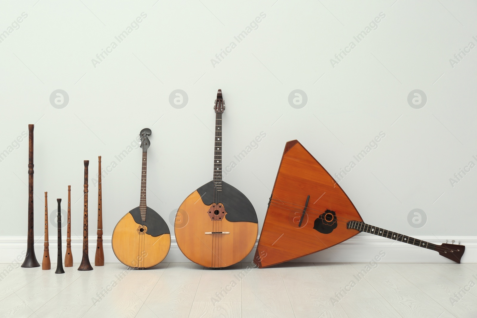 Photo of Set of different wooden musical instruments near white wall indoors