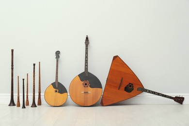 Set of different wooden musical instruments near white wall indoors