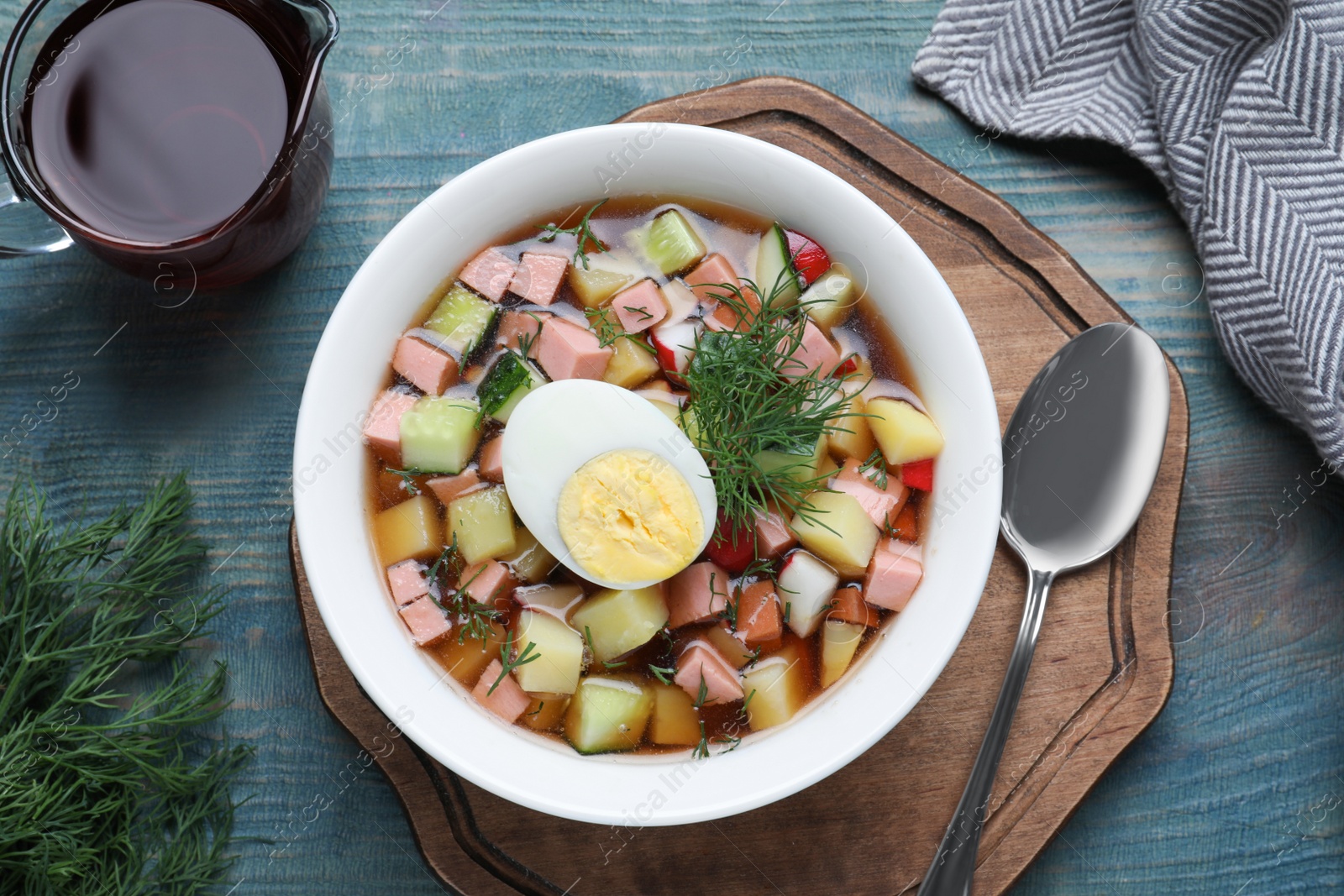 Photo of Delicious cold okroshka with kvass served on blue wooden table, flat lay. Traditional Russian summer soup