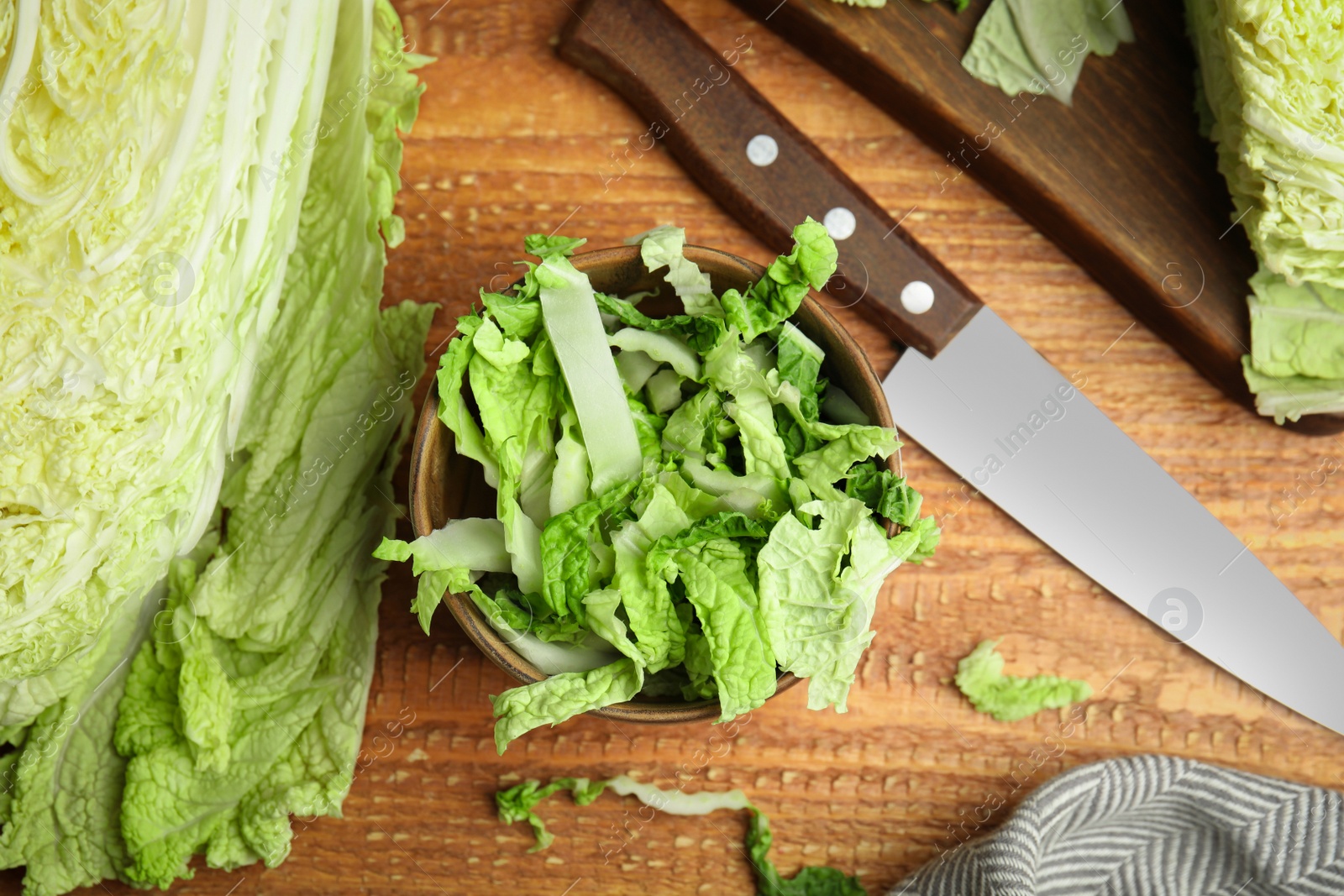 Photo of Chopped Chinese cabbage and knife on wooden table, flat lay