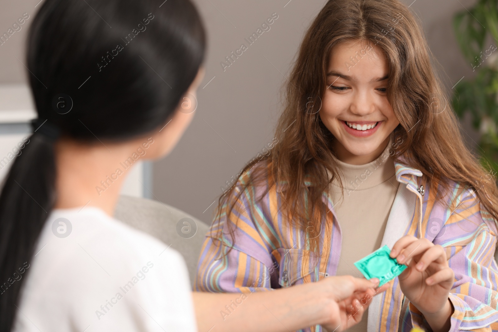 Photo of Mother giving condom to her teenage daughter at home. Sex education concept