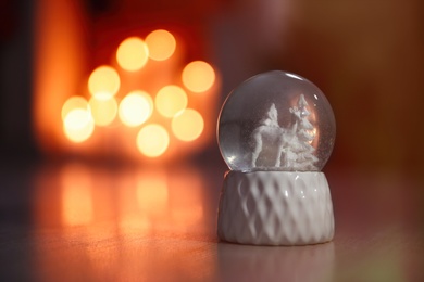 Photo of Snow globe on wooden table against blurred background, space for text. Bokeh effect