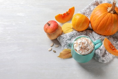 Photo of Cup with pumpkin spice latte, autumn decor and space for text on light table