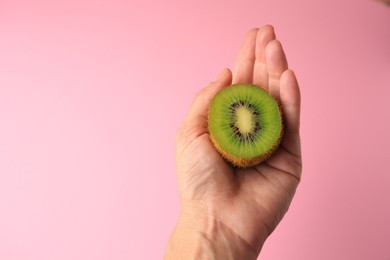 Photo of Woman holding delicious fresh kiwi on pink background, top view. Space for text