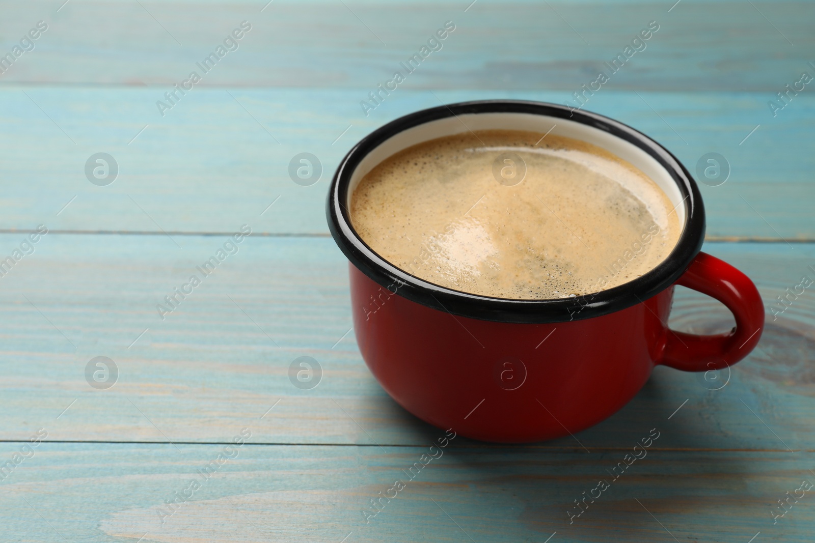 Photo of Cup of aromatic coffee on light blue wooden table, closeup. Space for text