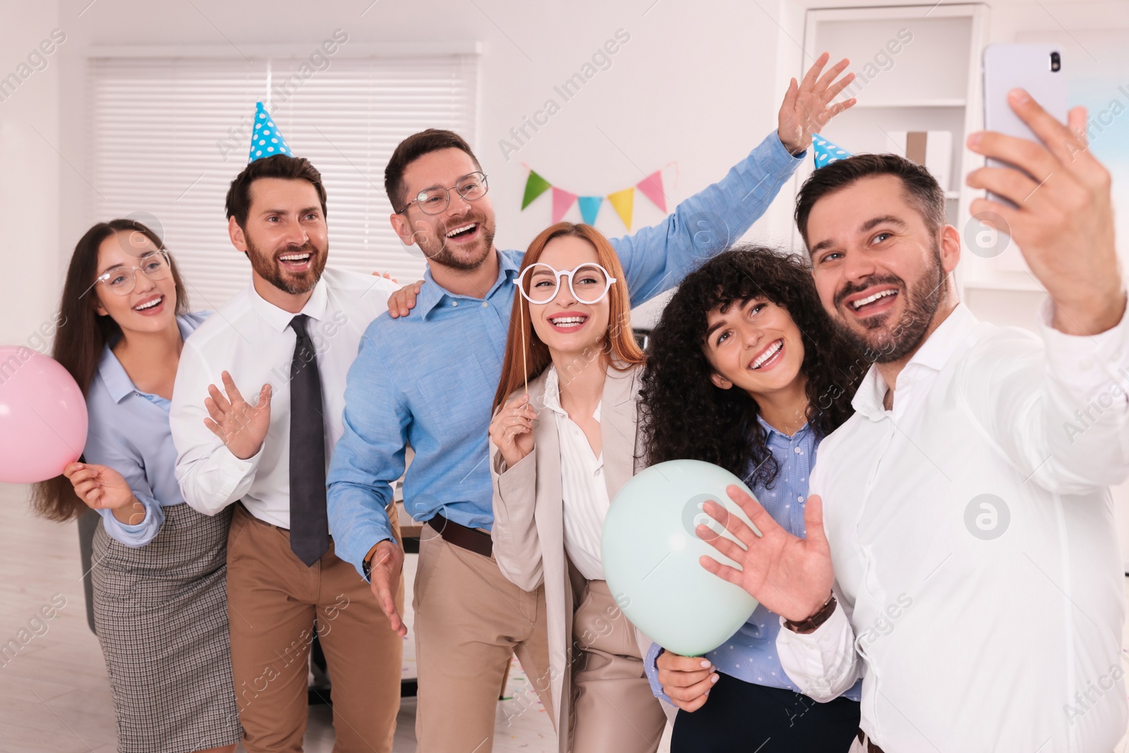 Photo of Coworkers taking selfie during office party indoors