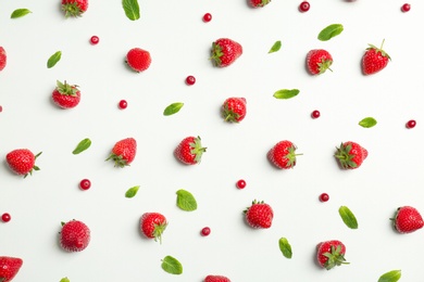 Flat lay composition with with tasty ripe strawberries, cranberries and mint on light background