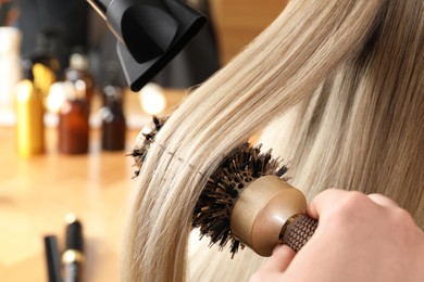 Photo of Hairdresser blow drying client's hair in salon, closeup
