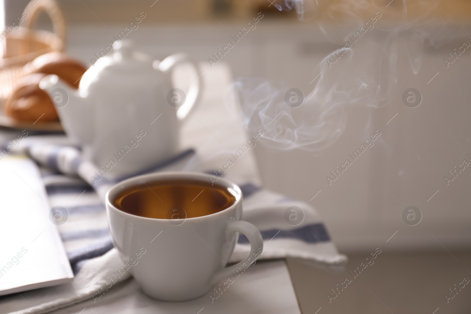 Photo of Cup of hot tea served for breakfast on table in kitchen