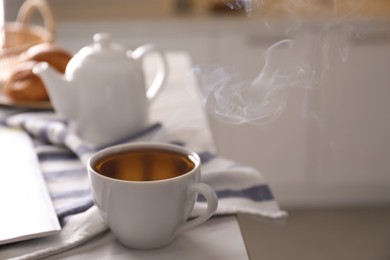 Photo of Cup of hot tea served for breakfast on table in kitchen