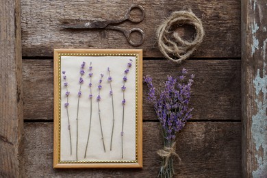 Photo of Beautiful lavender flowers, frame, twine and scissors on wooden table, flat lay