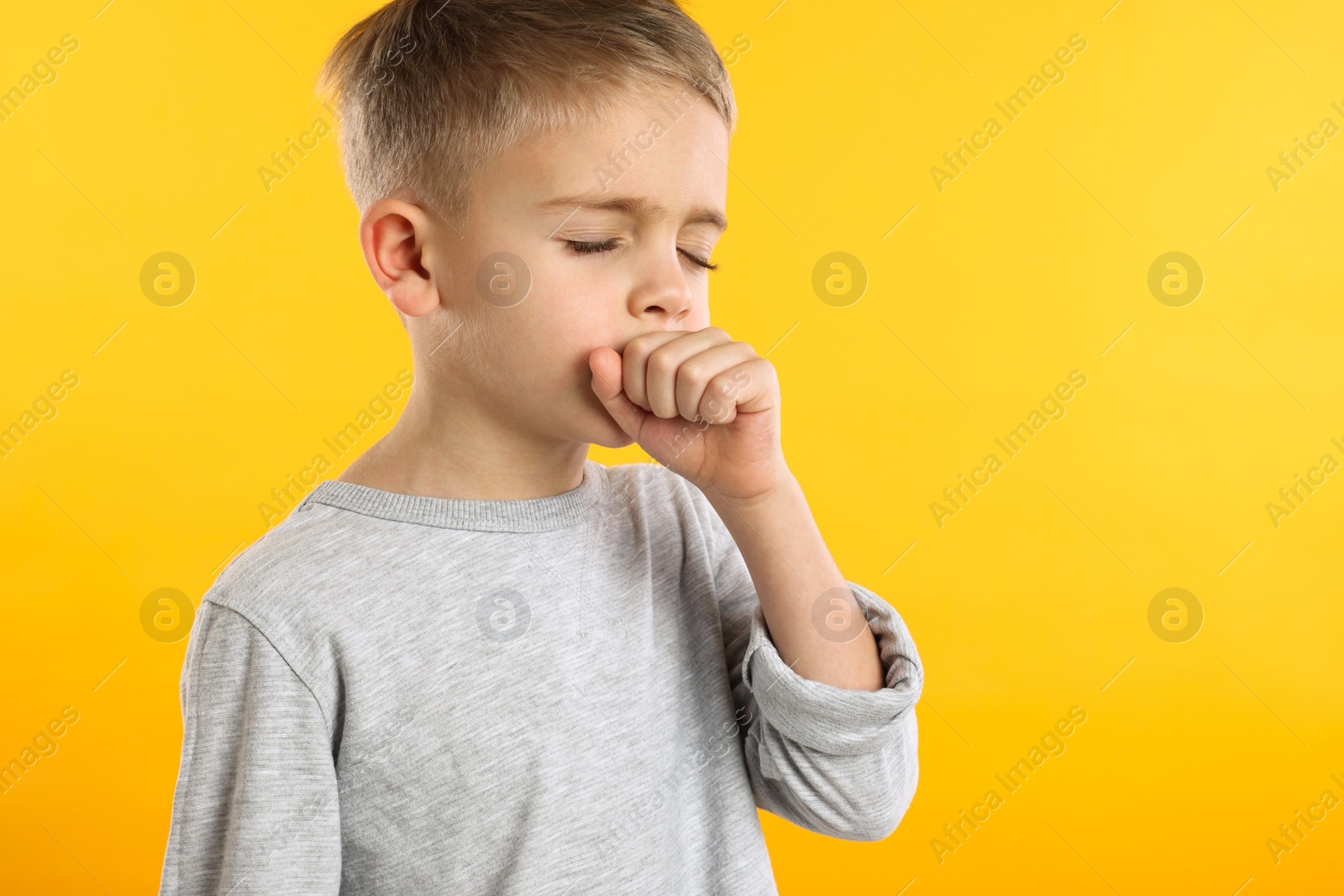 Photo of Sick boy coughing on yellow background. Cold symptoms