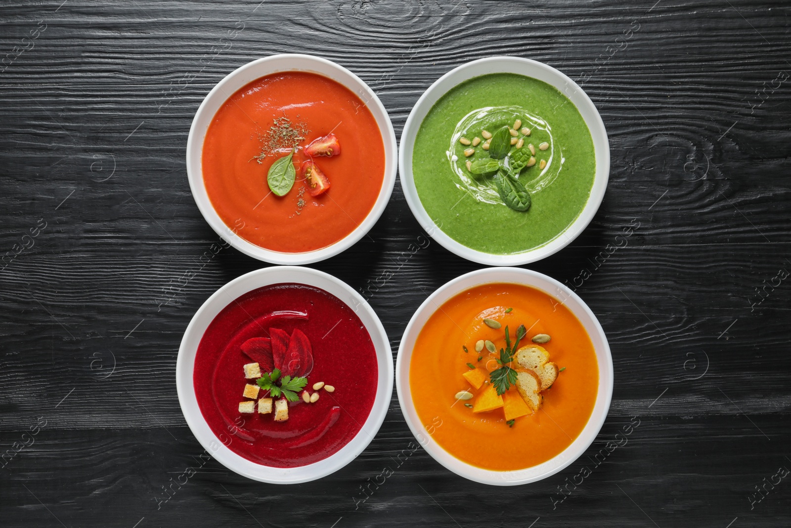 Photo of Various soups in bowls on wooden background, top view. Healthy food