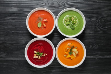 Various soups in bowls on wooden background, top view. Healthy food