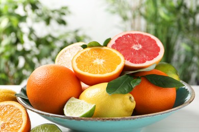 Photo of Different cut and whole citrus fruits on white table outdoors, closeup