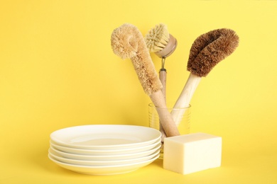 Photo of Cleaning supplies for dish washing and plates on yellow background