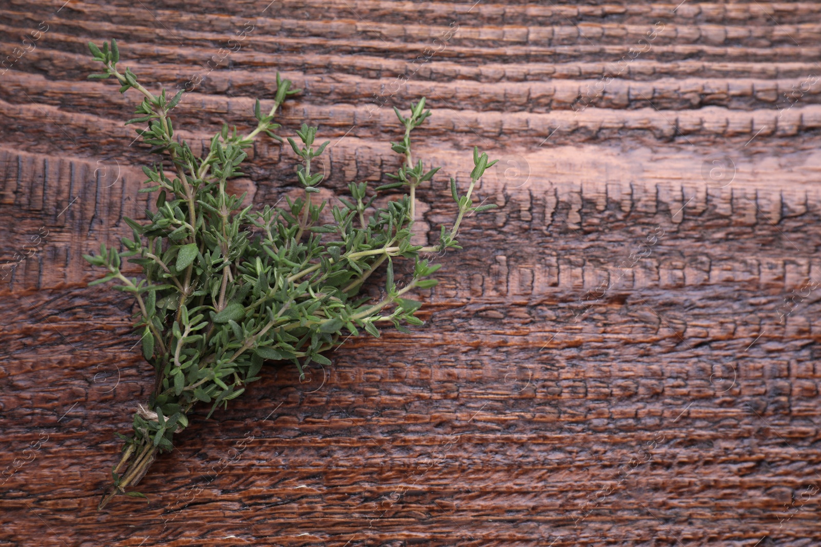 Photo of Bunch of fresh thyme on wooden table, top view. Space for text