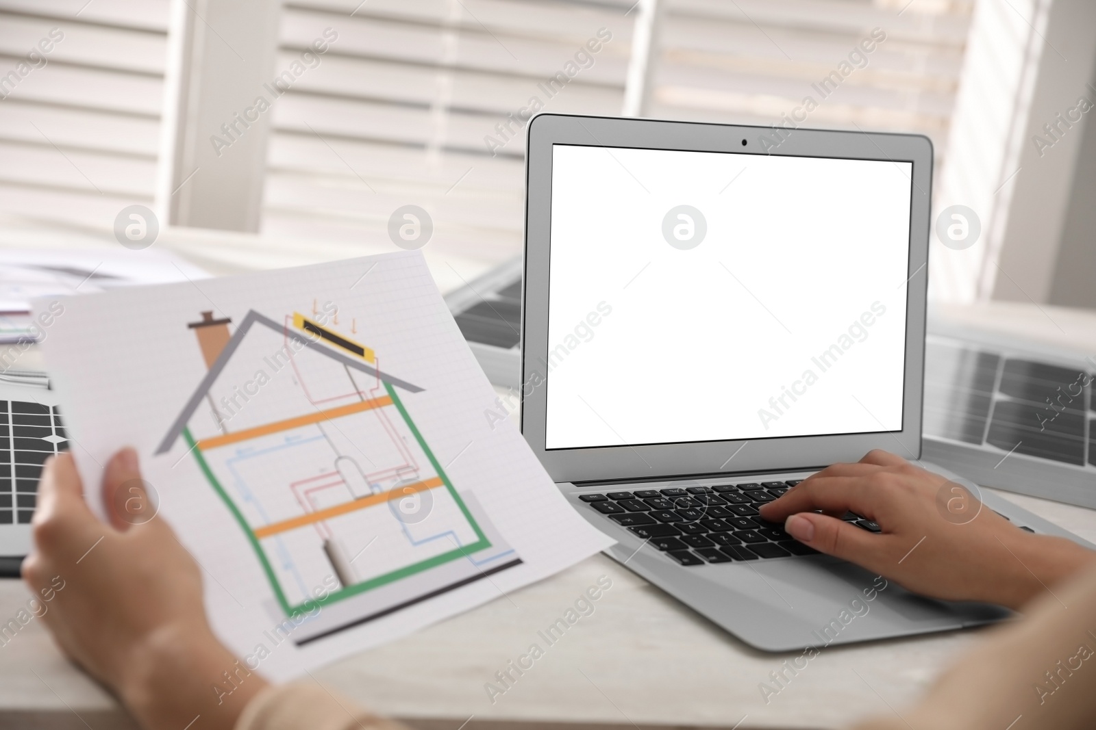 Photo of Woman working on house project with solar panels at table in office, closeup